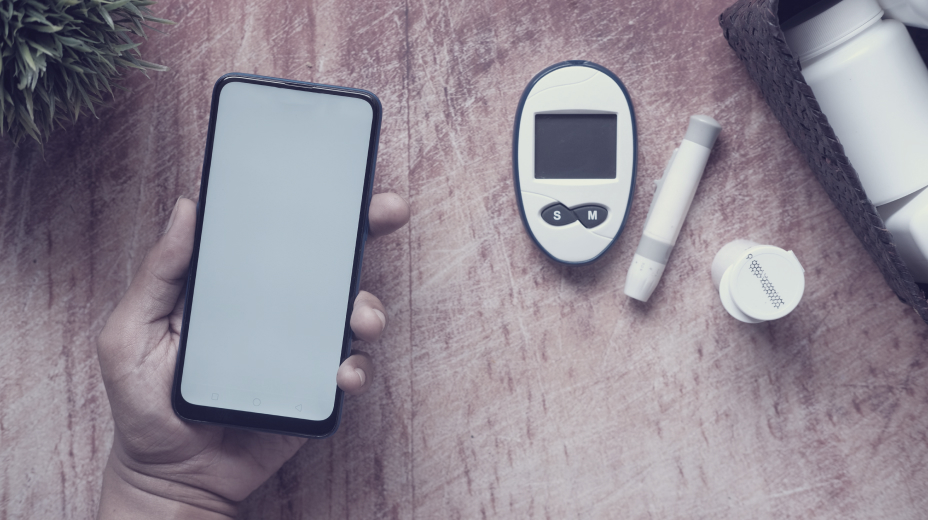 a person holding a smartphone beside diabetes tools